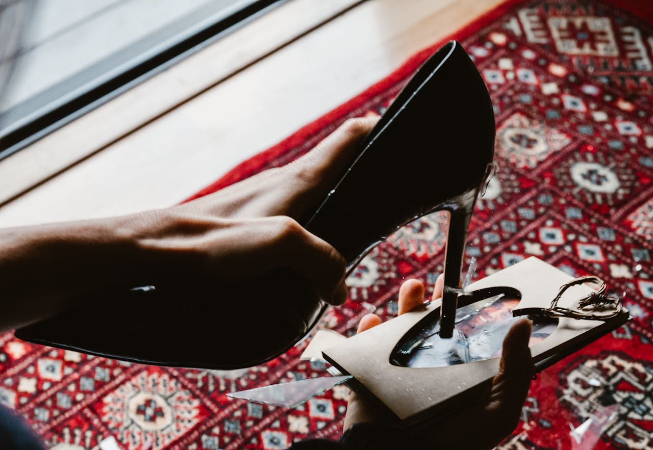 A black high heel stiletto piercing a heart-shaped photo on a vibrant Persian rug.