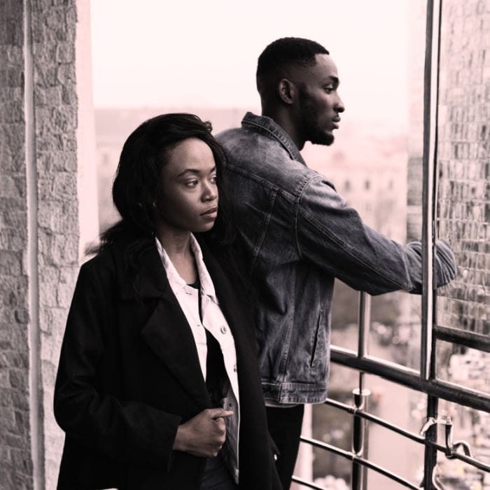 A woman standing next to a man who she feels disconnected from, representing the loneliness that can come from a situationship