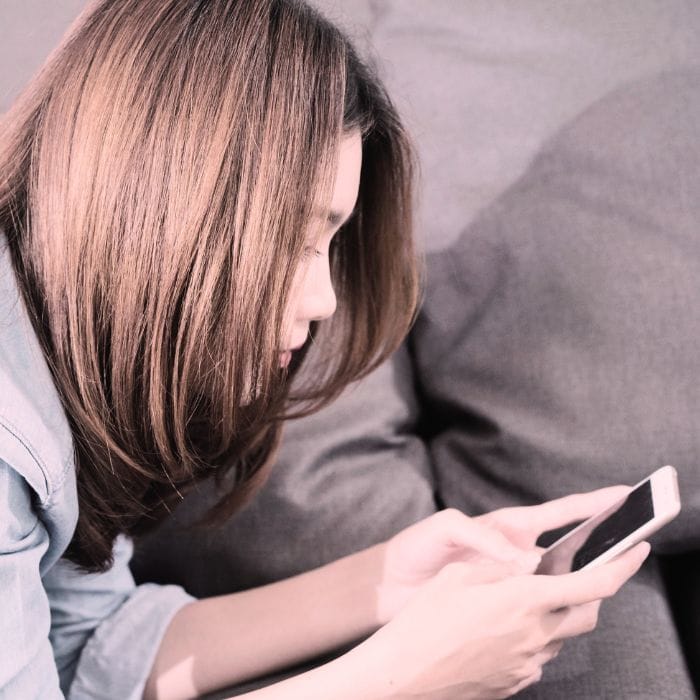 A woman sitting alone looking at her phone, reading a breakup text, representing the pain and confusion of a situationship ending without true closure.