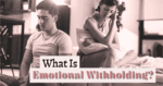 Couple sitting on a sofa with emotional distance between them, illustrating emotional withholding in a relationship.